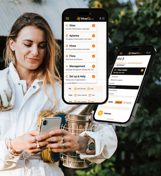 A photograph of a female beekeeper smiling while looking at her phone, with an image of the HiveIQ software displayed in the foreground. The software is showing a menu including links to Sites, Apiaries, Hives and Flora. . The beekeeper is wearing protective gear and standing in front of beehives in an apiary. This image illustrates the convenience of using HiveIQ software for beekeeping, allowing beekeepers to remotely monitor their hives and stay informed on their status while on-the-go.