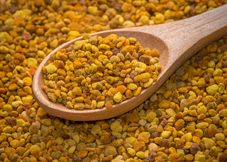 A close up image of bee pollen, it is being held in a wooden spoon